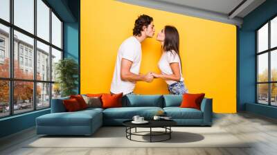 Young couple in love kiss isolated yellow background Wall mural